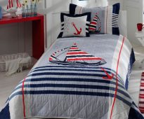 Baby bedspread on the bed for the boys in the marine style