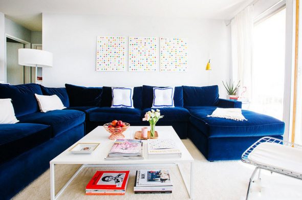 Duża niebieska sofa we wnętrzu jasnego salonu