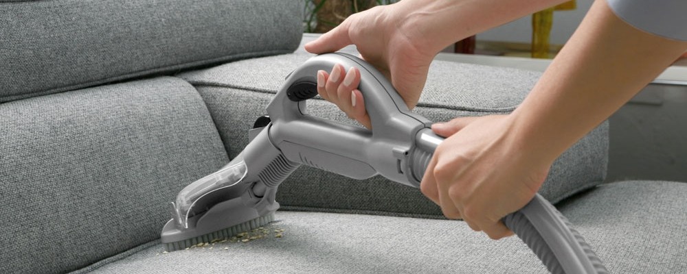 Cleaning the sofa with a vacuum cleaner