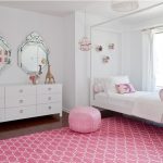 Bright pink carpet and pouf effect stand out against the white walls
