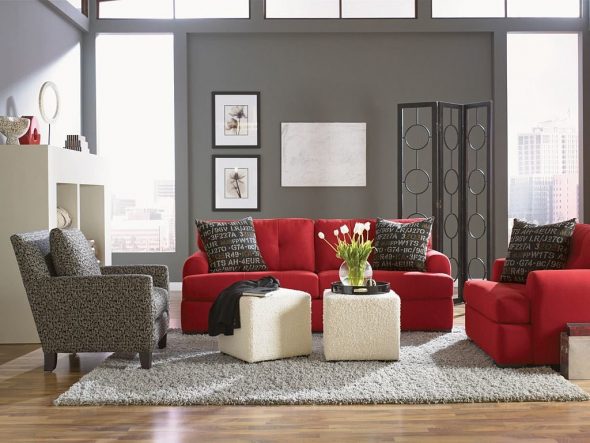 Suora punainen sohva sisustuksessa, jossa on kaksi tuolia
