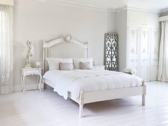 Wysoka szafa z rzeźbionymi wzorami i tradycyjnym średniowiecznym łóżkiem francuskim