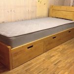single bed of tinted pine and storage boxes