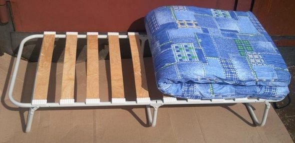 Children's folding bed with a mattress on the lamellae