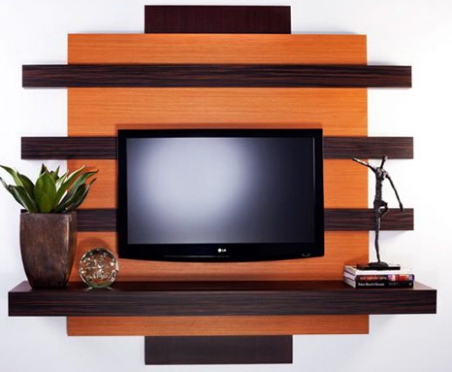Ściana telewizora jest ozdobiona półką oryginalnej formy w nieco ciemniejszej tonacji