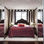 Eleganckie łóżko przy oknie w pokoju z szafkami lustrzanymi