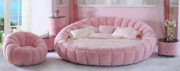 Różowe okrągłe łóżko z miękką różową otomaną