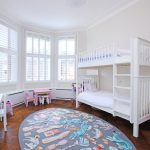 Pokój dziecięcy z białym drewnianym łóżkiem na dwóch poziomach