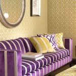 Fioletowa kanapa i fotel dobrze współgrają ze złotą żółcią
