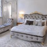 Piękne łóżko z miękkim oparciem i długą miękką otomaną w sypialni