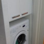 Niche sa banyo na may washing machine at isang cabinet sa itaas nito