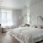 Szerokie łóżko z białym spiczastym zagłówkiem i białą jedwabną narzutą