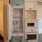 A refrigerator built into the cupboard and made in the same color and material as the entire kitchen unit
