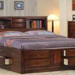 Drewniane łóżko z zagłówkiem w formie stojaka i wbudowanymi szufladami