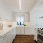 Witte ruime keuken met hoge kasten en jerrycans
