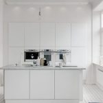 Snow-white kitchen with an island and high cabinets with canisters