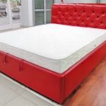 Czerwone skórzane łóżko z tapicerowanym zagłówkiem