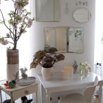 A small white table with mirrors of different sizes
