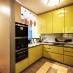 Geltona virtuvė su didelėmis sieninėmis spintelėmis