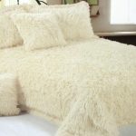 Ang beige fur blanket na may mga cushions ay mukhang napakarilag