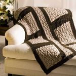 Beautiful plaid bedspread with braids on the sofa