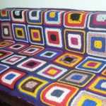 Plaid cover on the sofa from knitted square motifs