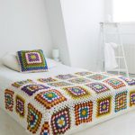 Large plaid on a bed with crocheted flower patterns