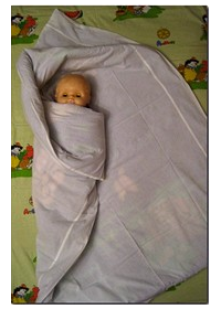 The left end of the blanket tightly wrapped baby