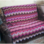 Plaid on a sofa of remnants of yarn, connected by multi-colored zigzag stripes