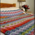 Multi-colored blanket with waves on a large bed