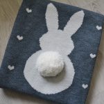 Original knitted blanket of wool yarn with a cute appliqué in the shape of a bunny