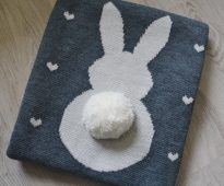 Original knitted blanket of wool yarn with a cute appliqué in the shape of a bunny