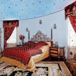 Burgundowe zasłony o sztywnym wzorze lambrekinów i tiulu w sypialni z wysokim sufitem