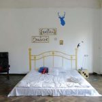 Mattress on the floor with painted bylets for decor in a minimally furnished room