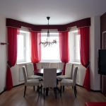 Straight burgundy curtains with hooks in the bay window