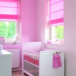 Small bed for a newborn in a room with two windows