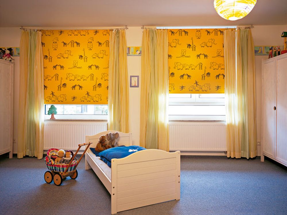 Yellow curtains with black print on the windows of the nursery
