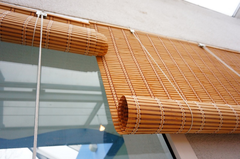 Rolowane zasłony z bambusowych pasków w oknie balkonowym
