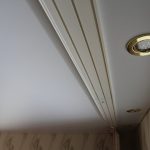 Ceiling cornice with fastening on a wooden beam and lighting in the ceiling