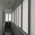 Dar bir balkonun pencerelerinde beyaz perdeler