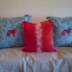 Blue pillows with red kittens and a red pillow in the middle