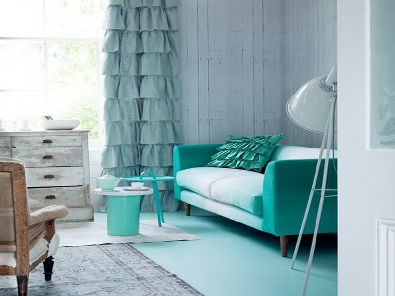 Turkusowa sofa obok zasłony w kolorze mięty