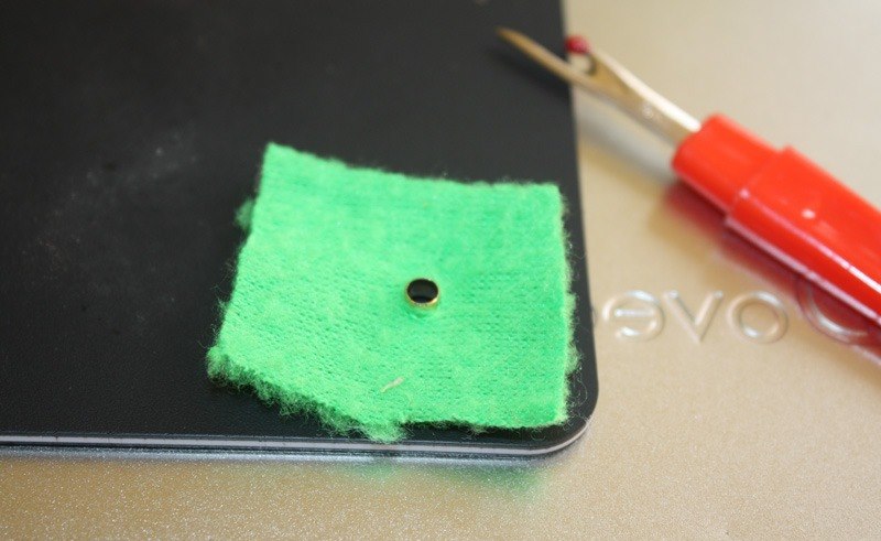 Przykład montażu oczka na kawałku zielonej tkaniny