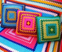 Plaid en kussens op de bank van de kleurrijke draden in de vorm van een vierkant