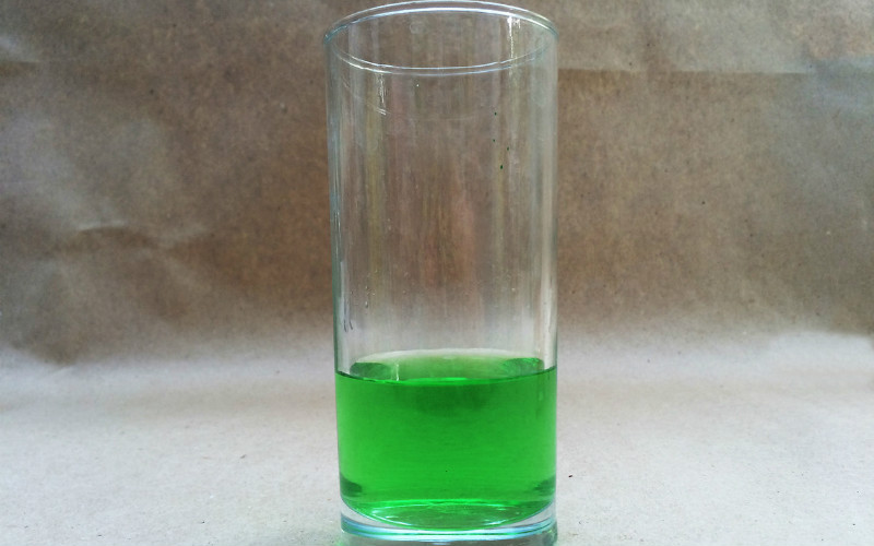 Szklany kubek z roztworem błyszczącej zieleni do mycia