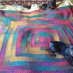 Multicolored blanket on the bed with 10 knit needles