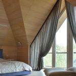 Eleganckie zasłony na trójkątnym oknie w sypialni na poddaszu