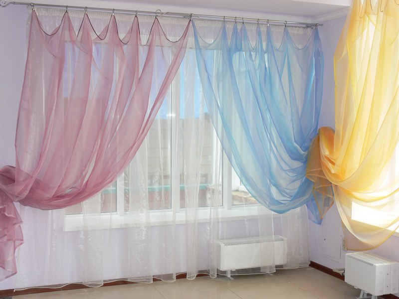 Mångfärgade gardiner av nylon på fönstren i hallen