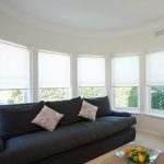 White blinds sa isang silid na may isang itim na sofa
