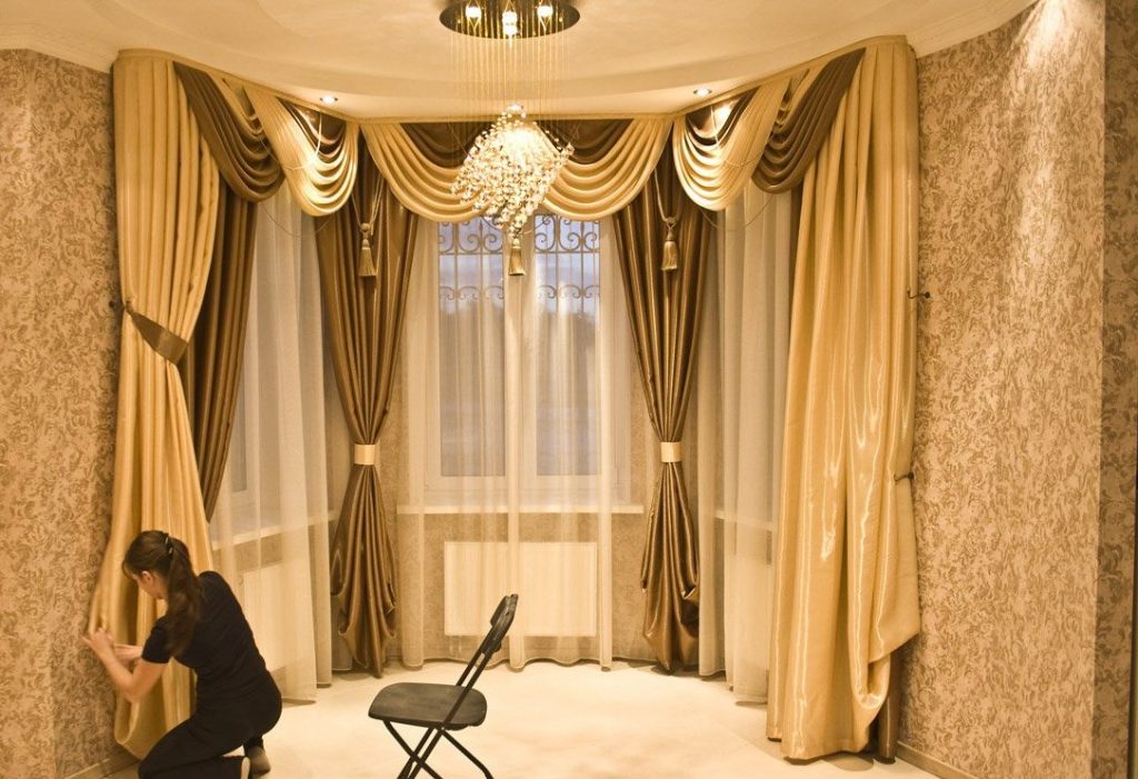 Beautiful curtains with lambrequin on the windows of the bay window in the hall of a private house